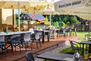 026.drewniany taras ze stolikami w ogrodzie przy placu zabaw dla rodzin restauracja dwa jeziora kal wegorzewo mazury