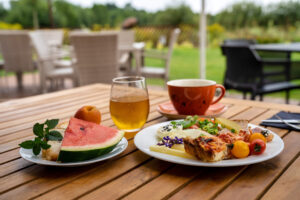 sniadanie na tarasie z widokiem na ogrod talerz arbuz i poranna kawa restauracja dwa jeziora kal wegorzewo mazury