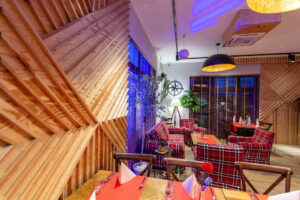 strefa lounge wieczorem fotele tartanowe drewniana sciana geometryczna restauracja dwa jeziora kal wegorzewo mazury