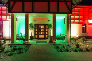 wejscie do recepcji wieczorem kolorowa iluminacja przy budynku glownym resortu ostoja dwa jeziora kal wegorzewo mazury