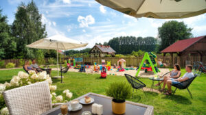 006 strefa kawiarniana para przy stoliku plac zabaw i budynek resortu w tle ostoja dwa jeziora kal wegorzewo mazury
